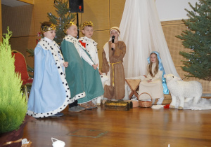 chłopcy jako trzej królowie stoją przy stajence i składają dary