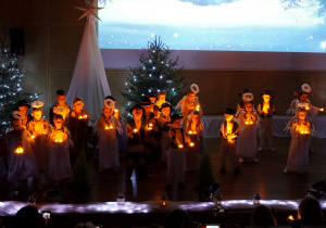 dzieci tańczą i śpiewają pastorałkę ze światełkami