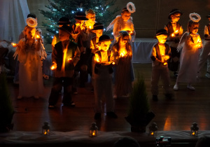 dzieci tańczą i śpiewają pastorałkę ze światełkami