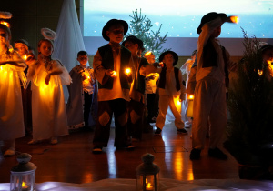 dzieci tańczą i śpiewają pastorałkę ze światełkami