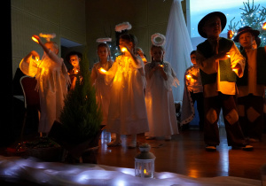 dzieci tańczą i śpiewają pastorałkę ze światełkami
