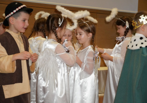 dzieci dzielą się opłatkiem i składają sobie życzenia