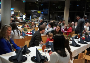 rodzice siedzą przy stolach podczas poczęstunku wigilijnego