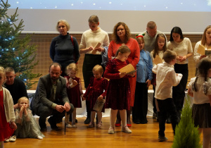 Rodzice z dziećmi śpiewają na scenie kolędy