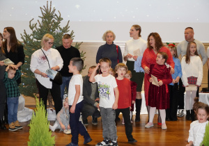 Rodzice z dziećmi śpiewają na scenie kolędy