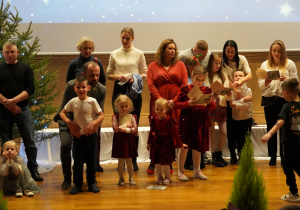 Rodzice z dziećmi śpiewają na scenie kolędy