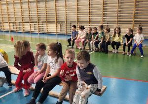 dzieci siedzą na ławeczkach