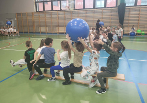 dzieci nad głowami podają sobie piłkę