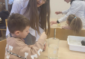 chłopiec wraz z uczenicą wykonują doświadczenie