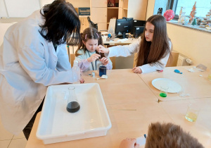 dziewczynka wraz z uczenicami wykonuje doświadczenie chemiczne