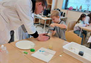 chłopiec wraz z uczniami wykonuje eksperyment chemiczny