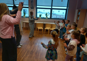 dzieci stojąw w półkolu wraz z uczniami, pokazując i śpiewająć utwór w j.angielskim