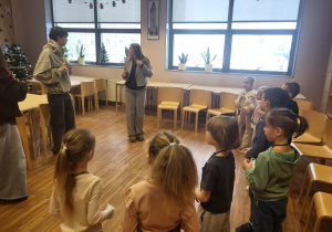 dzieci stoją w półkolu,słuchając uczniów