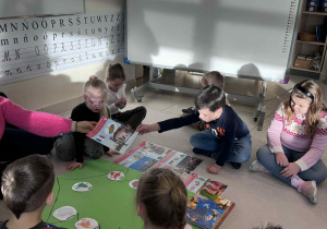 dzieci siedzą w kole,a Pani poduje chłopcu plakat