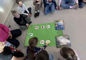 dzieci siedzą w kole i układają na narysowanej choince "ozdoby"z konturami i nazwami kontynentów
