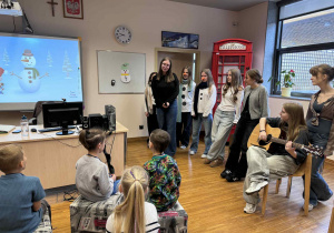 dzieci siedzą i słuchają w języku angielskim piosenki o bałwanku