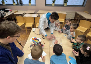 dzieci obserwują przy stoliku uważnie eksperyment z cięciem lodu