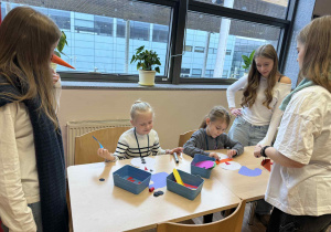 dziewczynki siedzą przy stoliku wykonując papierowe bałwanki