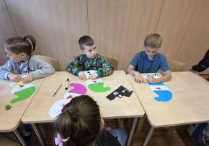 dziewci siedzą przy stoliku wykonując papierowe bałwanki