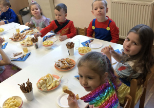 dzieci siedzą przy stolikach