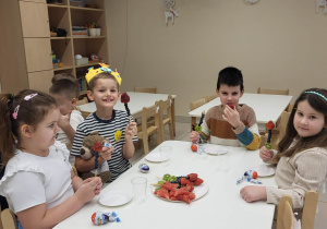 Dzieci jedzą owoce przy stoliku