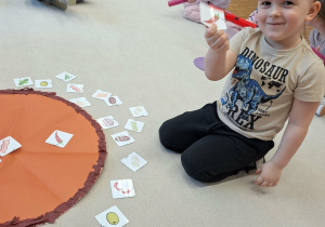 dziecko kładzie na pizzy składniki