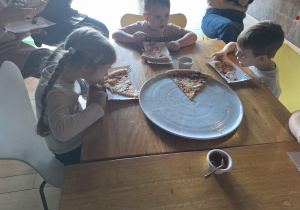 dzieci jedzą pizzę