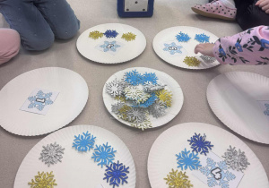 talarzyki leżące na dywanie ze śnieżynkami oraz liczbami i kostką do grt