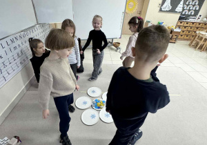 dzieci chodzią wokół talerzyków ze śnieżynkami grając w gre "maths is action"