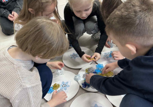 dzieci liczą śnieżynki i kładą na odpowiednią liczbę na talerzyku