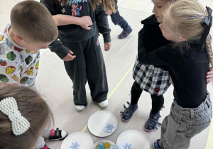 zieci chodzią wokół talerzyków ze śnieżynkami grając w gre "maths is action"