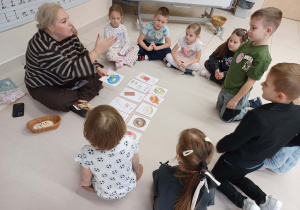 dzieci siedzą w kole z panią i bawią się zabawę "jaki smak pączka"?