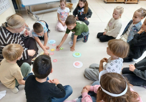 dzieci siedzą w kole i sortują pączki według koloru i ilości