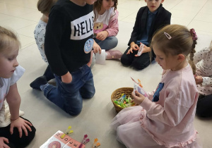 dzieci siedzą w kole i wykonują literkowe zadanie z klamerkami