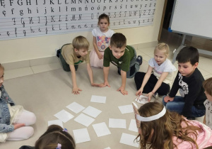 dzieci siedzą w kole i grają w memory z pączkami