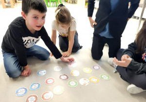 chłopiec i dziewczynka wykonują zadanie polegajace na połączeniu połówki pączków, na których sa literki