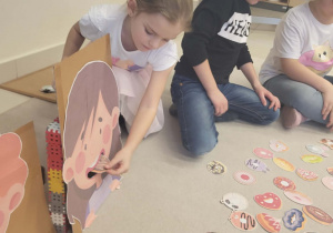 dziewczynka wkłada do pudełka z wizerunkiem dziewczynki pączka