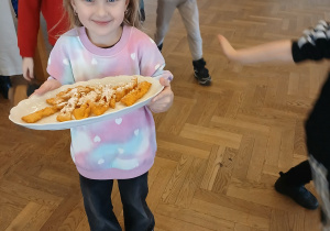 Dziewczynka niesie faworki na stół