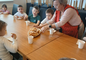 Pani podaje pączki do stołu