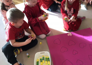 dzieci przykleją serca na karton