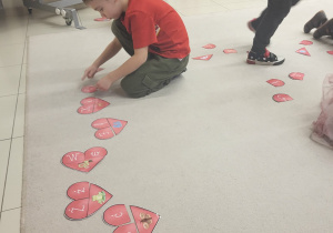 chłopiec układa serca na dywanie