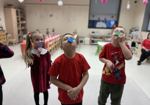 dzieci zgodnie z poleceniem trzymają serduszka na ustach