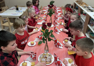 dzieci siedzą przy stole podczas walentynkowego poczęstunku
