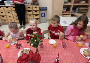 dzieci siedzą przy stole i jedzą babeczki