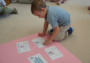 chłopiec przykleja obrazek na kartonie