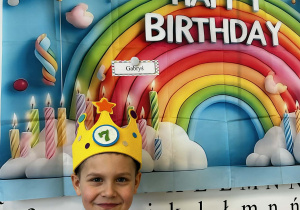 Chłopiec pozuje w koronie na urodzinowym tle