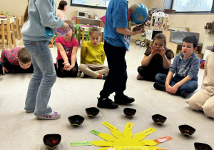 Chłopiec trzyma globus a dziewczynka rozkłada koraliki