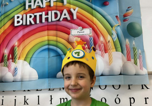 Chłopiec pozuje w koronie na urodzinowym tle