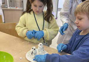 chłopiec i dziewczynka lepią bałwanka ze sztucznego śniegu