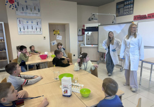 dzieci siedzą w ławkach na zajeciach z chemii i słuchają o czym będą zajęcia